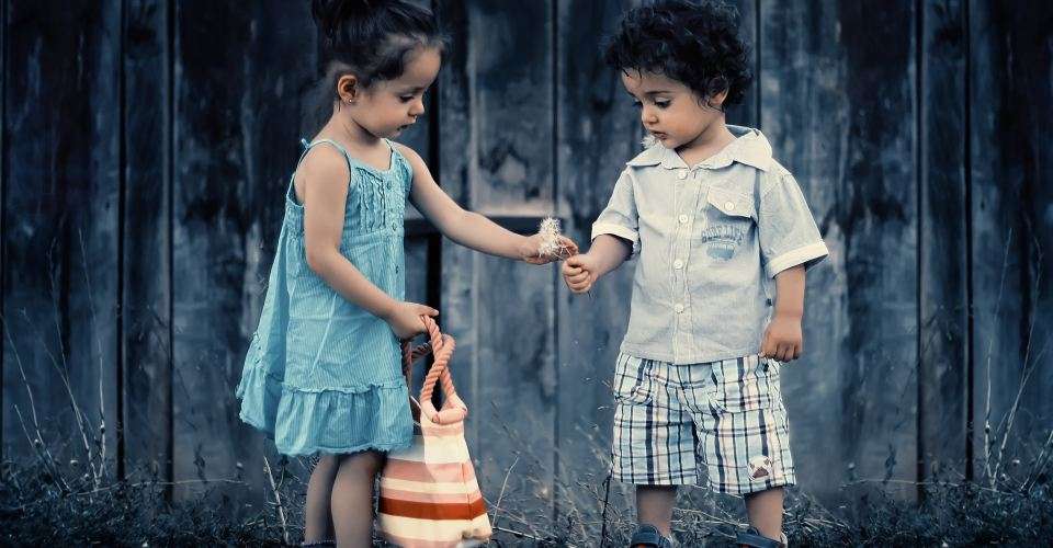 Une petite fille et un petit garçon tenant une fleur.